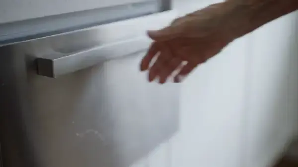 Frosted gel pouch lifted out of a freezer drawer by one hand